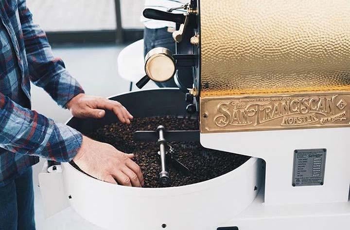 Left image: a man in a blue flannel shirt roasting coffee beans in a white and gold roaster. Right image: a man in a blue flannel shirt working on a black and gold roaster.